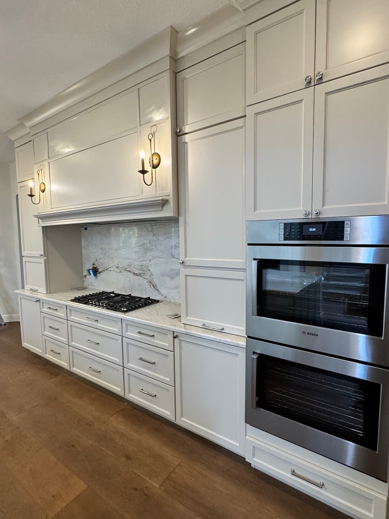 Kitchen remodel with white cabinets, range hood, and double oven in Tampa